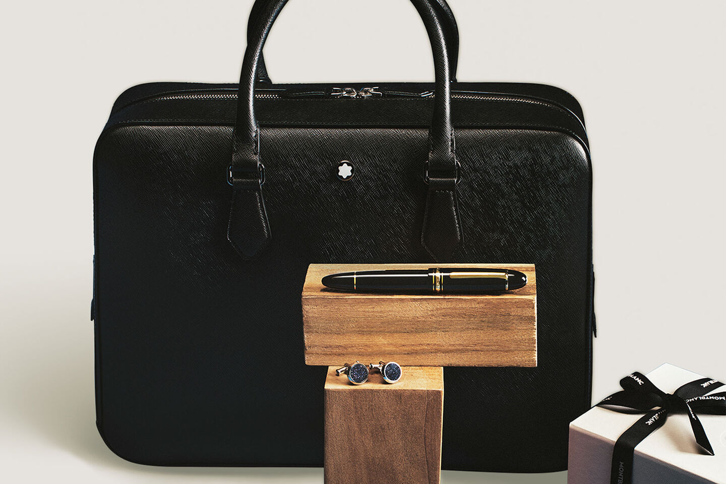 Montblanc black leather briefcase, Meisterst&uuml;ck fountain pen, and elegant blue cufflinks, displayed with a branded gift box.