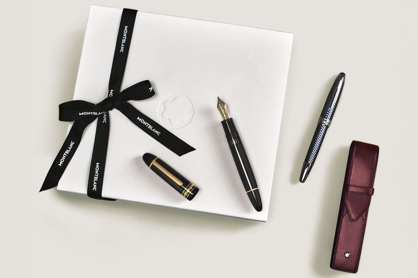 Montblanc black Meisterst&uuml;ck fountain pen, and a burgundy leather pen pouch, displayed with a branded white gift box.